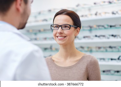 Health Care, People, Eyesight And Vision Concept - Happy Woman In Glasses Looking And Talking To Optician At Optics Store