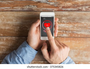 health care, people and technology concept - close up of male hands holding smartphone and pointing finger heart- rate icon on screen - Powered by Shutterstock