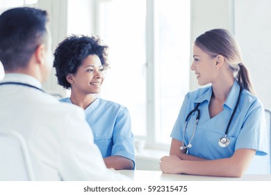 Health Care, Profession, People And Medicine Concept - Group Of Happy Doctors Or Nurses Meeting And Talking At Hospital