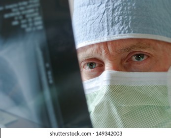 Health Care Professional  Intensely Studies X-ray Results Prior To Surgery. Selective Focus On Eyes.  Would Make Good Hospital, Physician, Doctor, Surgeon Illustration. Photographer As Model. 