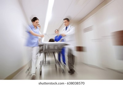 health care, reanimation and medicine concept - group of medics or doctors carrying unconscious woman patient on hospital gurney to emergency (motion blur effect) - Shutterstock ID 638038570