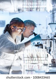 Health Care Researchers Working In Life Science Laboratory. Young Female Research Scientist And Senior Male Supervisor Preparing And Analyzing Microscope Slides In Research Lab.