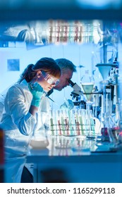 Health Care Researchers Working In Life Science Laboratory. Young Female Research Scientist And Senior Male Supervisor Preparing And Analyzing Microscope Slides In Research Lab.