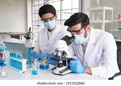 Health care researchers working in life science laboratory. Male research scientist and supervisor preparing and analyzing microscope slides in research lab. The invention of the coronavirus vaccine.