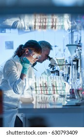 Health Care Researchers Working In Life Science Laboratory. Young Female Research Scientist And Senior Male Supervisor Preparing And Analyzing Microscope Slides In Research Lab.