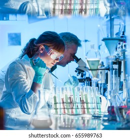 Health Care Researchers Working In Life Science Laboratory. Young Female Research Scientist And Senior Male Supervisor Preparing And Analyzing Microscope Slides In Research Lab.