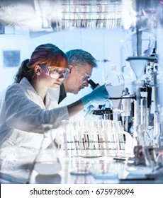 Health Care Researchers Working In Life Science Laboratory. Young Female Research Scientist And Senior Male Supervisor Preparing And Analyzing Microscope Slides In Research Lab.