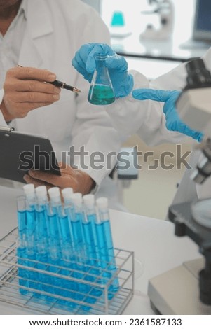 Health care researchers working in life science laboratory. Young female research scientist and senior male supervisor preparing and analyzing microscope slides in research lab.