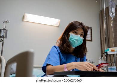 Health care series: Asian woman patient sit watching TV on hospital bed, holding smart-phone