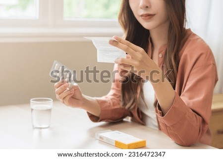 Health care treatment asian young woman holding prescription of capsule medicine, reading label text about medical information, looking medicine instruction side effects, pharmacy medicament concept.