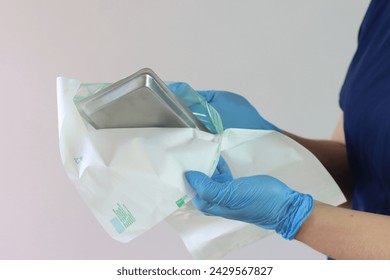 Health care worker opening a sterile pack with care to not contaminate the sterile material for a procedure  - Powered by Shutterstock