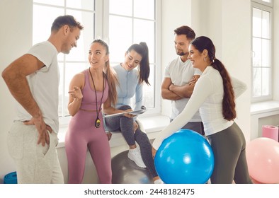 Health centre and fitness club sporty people talking with slim female coach. Discuss how to improve results, overall health and wellness by participating in fitness games, strength training, exercises - Powered by Shutterstock