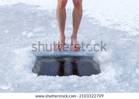 Health and cold water hardening. Man and ice hole. Legs and ice hole close-up.