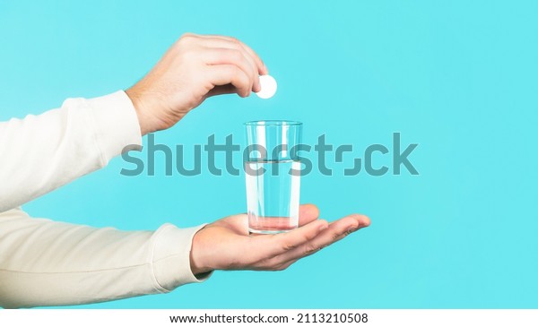Health concept. Close up of man holding a pill.\
Glass of water tablet. Glass with efervescent tablet in water with\
bubbles.