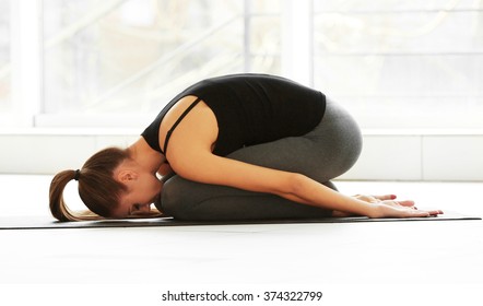 Health concept. Young attractive woman does yoga exercise in the gym  against window - Shutterstock ID 374322799