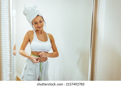 Health Conscious Woman Standing In Front Of A Bathroom Mirror. She Is Pinching An Inch From Her Waist. She Is Excited To See That Her Waistline Is Shrinking Due To Her Current Diet Plan. 