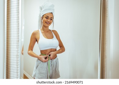 Health Conscious Woman Standing In Front Of A Bathroom Mirror. She Is Pinching An Inch From Her Waist. She Is Excited To See That Her Waistline Is Shrinking Due To Her Current Diet Plan. 