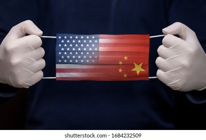 Health Employee Doctor Holding Medical Face Mask The USA And China Flags. Coronavirus (COVID-19) Pandemic Affects The Country. 