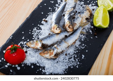 Health food. Delicious sardines baked in oven on pillow of sea salt with spices, lime and tomato