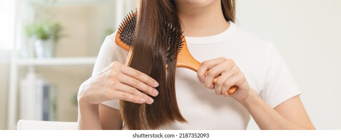 Health hair care, beauty makeup asian woman, girl holding hairbrush and brushing, combing her long straight hair looking at reflection in mirror in morning routine after salon treatment, hairstyle.