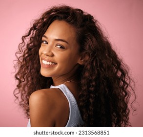 Health, hair care and portrait of a woman in a studio with a natural, long and curly hairstyle. Happy, smile and brunette female model with beauty keratin salon treatment isolated by pink background. - Powered by Shutterstock