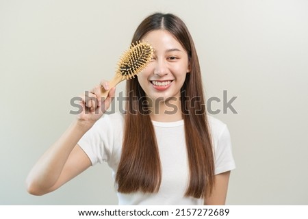 Health hair care, smile beautiful asian woman hand in holding hairbrush and brushing, combing her long straight hair in the morning routine after salon treatment, hairstyle. Isolated on background.