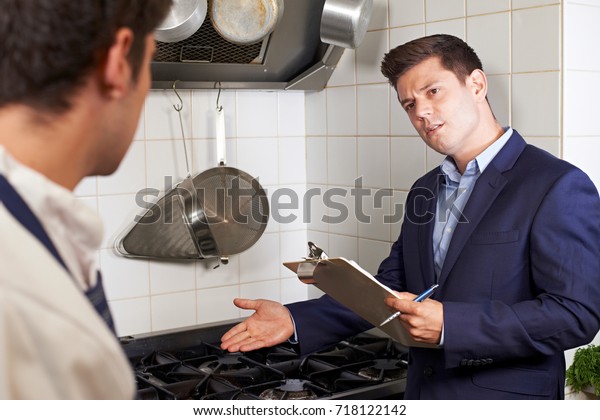 Health\
Inspector Meeting With Chef In Restaurant\
Kitchen