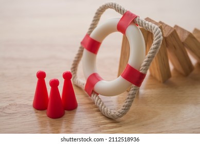 Health insurance or life insurance business and health care concept. Lifebuoy stop wood block fall domino crisis effect to people model on office wooden table background copy space. Risk management.