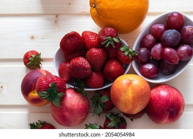 Health and life benefits of strawberries, grapes, nectarines, oranges; high angle photo of fruit on traditional wooden background - Shutterstock ID 2054054984