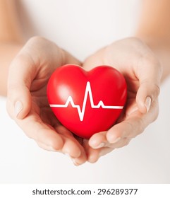 Health, Medicine And Charity Concept - Closeup Of Female Hands Holding Red Heart With Ecg Line