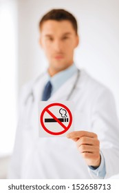 Health, Medicine And Hospital Concept - Male Doctor Holding No Smoking Sign In Hands