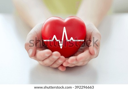 health, medicine, people and cardiology concept - close up of hand with cardiogram on small red heart