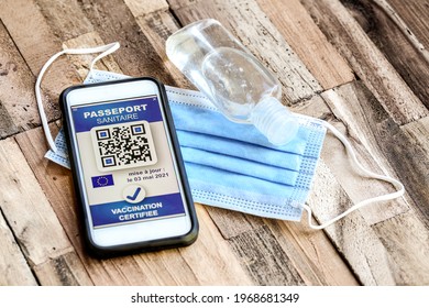 health passport on wooden table with the french text "passeport sanitaire" means "digital green pass" and  "vaccination certifiée" means "certified vaccination" - Shutterstock ID 1968681349