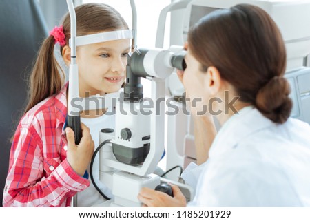 Health problem. Nice pretty girl visiting a doctor while having her eyesight checked