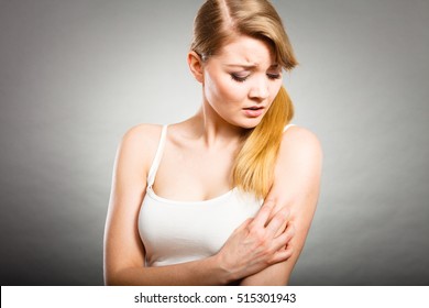 Health problem, skin diseases. Young woman scratching her itchy arm with allergy rash