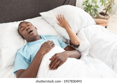 Health Problems, Deep Sleep And Apnea, Noise And Bad Night. Young African American Guy Snoring, Lady Suffering And Covering Her Face With Pillow So No Hear Man In Bed In Bedroom Interior, Empty Space