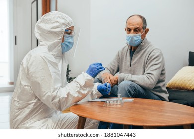 Health Professional In A PPE Suit, Mask, Face Shield Taking A Nasal Culture Sample In The Coronavirus Pandemic During A Home Visit. Antigen Test Of An Elderly Patient.