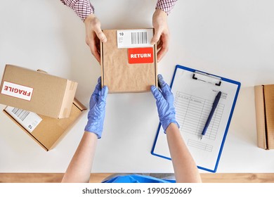 health protection, delivery and mail service concept - customer making return of parcel or purchase and worker in protective gloves receiving box - Shutterstock ID 1990520669