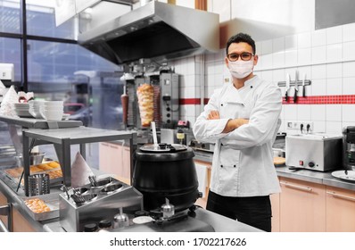 Health Protection, Safety And Pandemic Concept - Male Chef Cook Wearing Face Protective Medical Mask Over Kebab Shop Kitchen Background