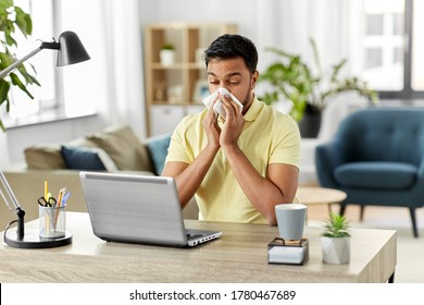 Health, Remote Job And People Concept - Sick Young Indian Man With Laptop Computer Blowing Nose At Home Office