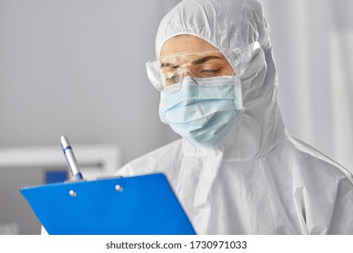 Health Safety, Medicine And Pandemic Concept - Close Up Of Female Doctor Or Scientist In Protective Wear, Medical Mask And Goggles For Protection From Virus Disease With Clipboard