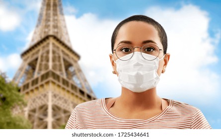 Health, Safety And Pandemic Concept - Young African American Woman Wearing Medical Face Mask For Protection From Virus Disease Over Eiffel Tower In Paris, France Background