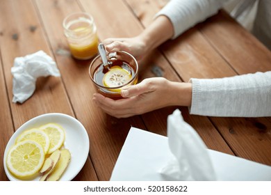 health, traditional medicine and ethnoscience concept - ill woman drinking tea with lemon, honey and ginger and paper wipes box on wooden table - Powered by Shutterstock