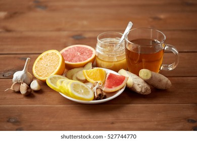 health, traditional medicine, folk remedy and ethnoscience concept - cup of ginger tea with honey, citrus and garlic on wooden background - Shutterstock ID 527744770