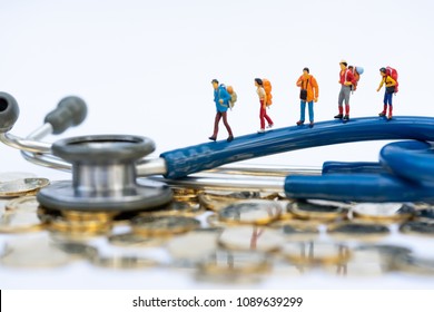 Health And Travel Insurance, Miniature People, Traveler With Backpack Walking On  Stethoscope. Business, Health Care, And Traveling Concept.