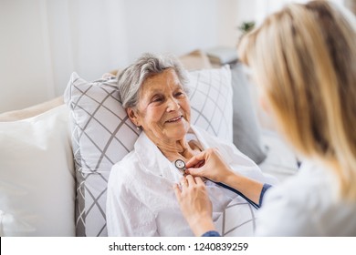 A health visitor examining a sick senior woman lying in bed at home with stethoscope. - Shutterstock ID 1240839259
