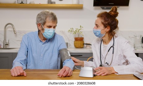 Health Visitor And A Senior Man During Home Visit. A Female Nurse Or A Doctor Examining A Man.