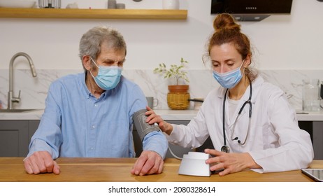 Health Visitor And A Senior Man During Home Visit. A Female Nurse Or A Doctor Examining A Man.