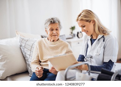 A health visitor and a senior woman sitting on a bed at home, talking.