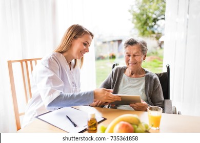 Health visitor and a senior woman with tablet.